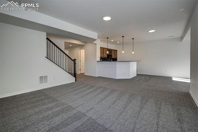 unfurnished living room with visible vents, recessed lighting, stairway, dark colored carpet, and baseboards