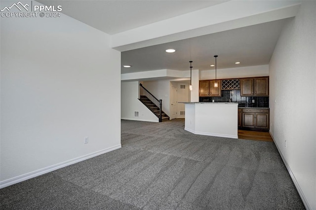 kitchen featuring decorative light fixtures, dark carpet, tasteful backsplash, and a kitchen island