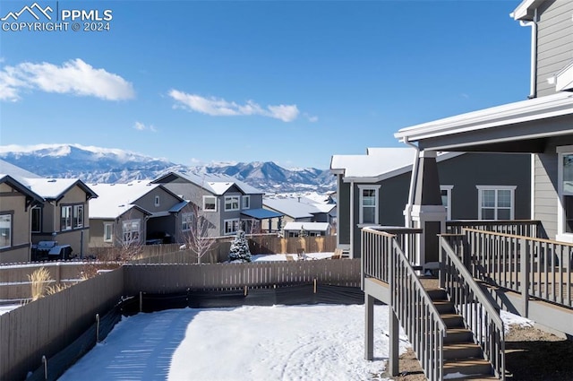 snowy yard featuring a residential view, a mountain view, and fence private yard