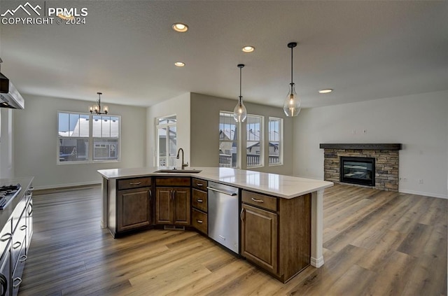 kitchen featuring recessed lighting, a sink, a stone fireplace, stainless steel dishwasher, and light wood-type flooring