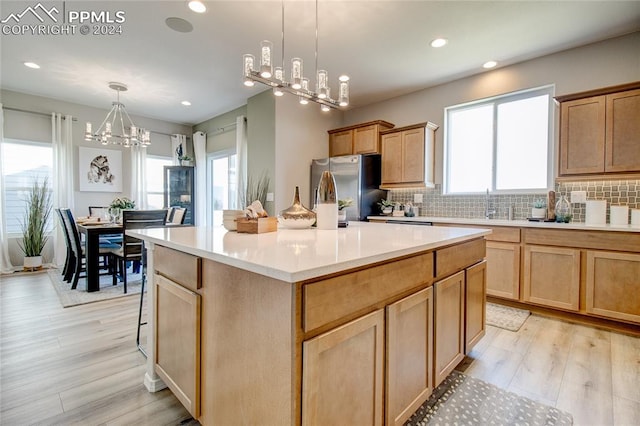 kitchen with a center island, light hardwood / wood-style floors, tasteful backsplash, and stainless steel refrigerator