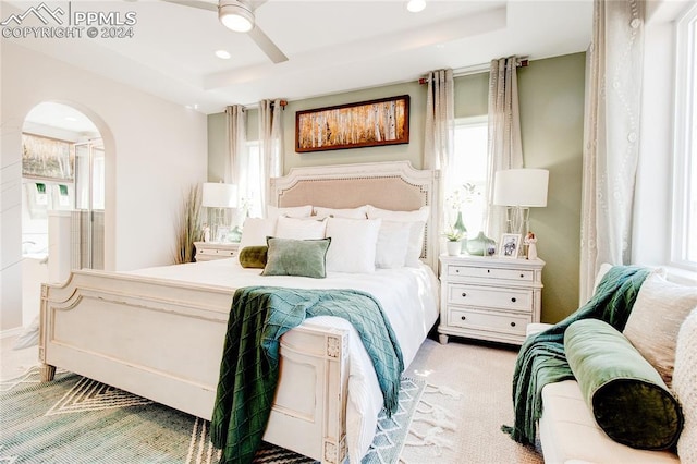 bedroom featuring carpet, a raised ceiling, arched walkways, and recessed lighting