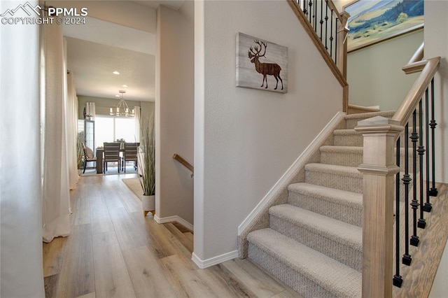 staircase with light hardwood / wood-style floors and a notable chandelier