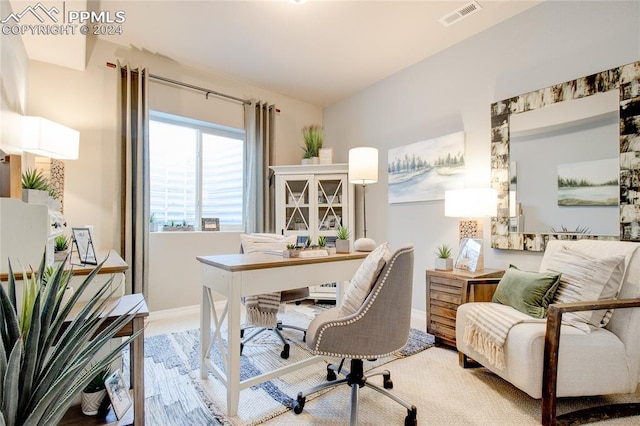 office area with wood finished floors, visible vents, and baseboards