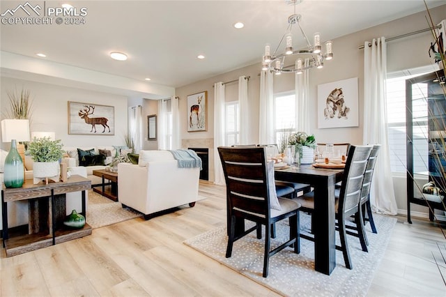 dining space with light wood finished floors, a tile fireplace, and recessed lighting