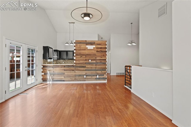 interior space featuring a towering ceiling, wood-type flooring, and french doors