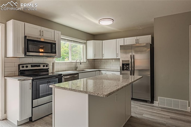 kitchen with backsplash, a center island, appliances with stainless steel finishes, and light wood-type flooring