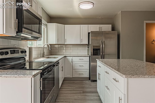 kitchen with appliances with stainless steel finishes, white cabinets, sink, decorative backsplash, and wood-type flooring