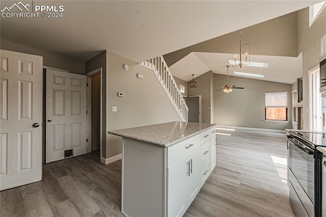 kitchen featuring black electric range, a center island, white cabinetry, ceiling fan, and wood-type flooring