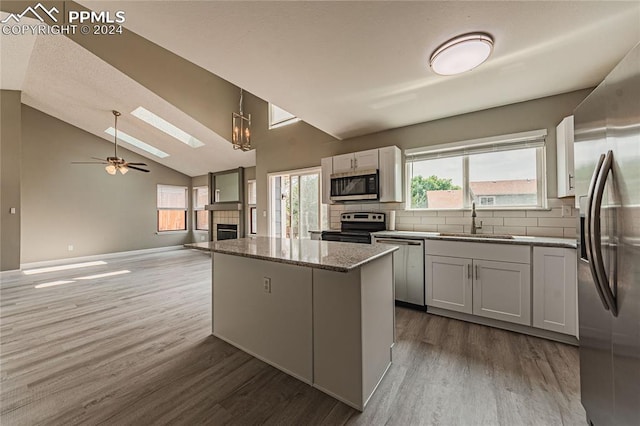 kitchen featuring lofted ceiling, wood-type flooring, backsplash, and stainless steel appliances