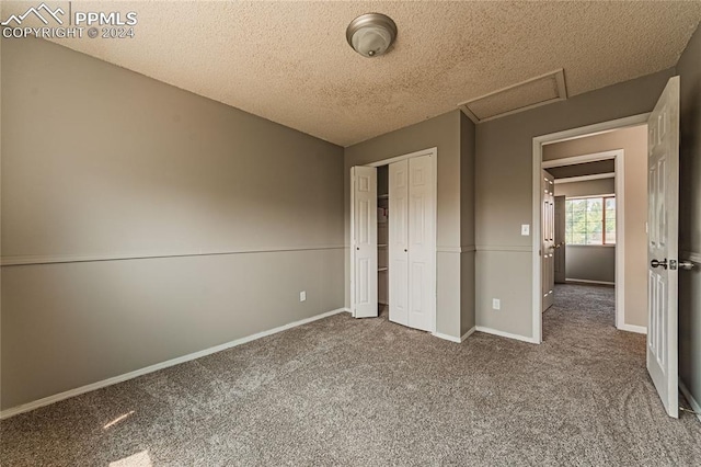 unfurnished bedroom featuring carpet floors, a textured ceiling, and a closet