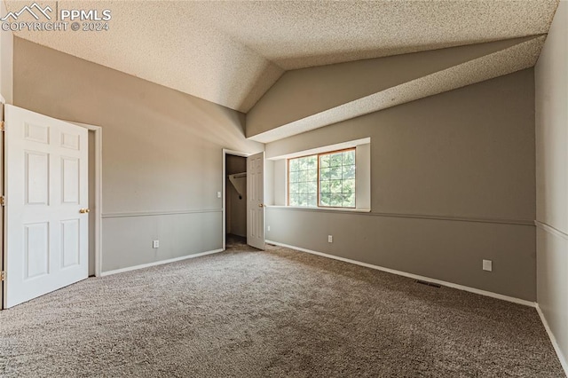 unfurnished bedroom featuring carpet, a textured ceiling, and vaulted ceiling