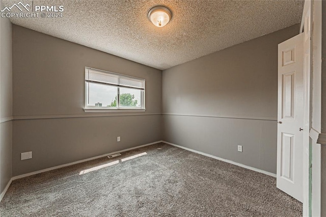 spare room featuring carpet flooring and a textured ceiling