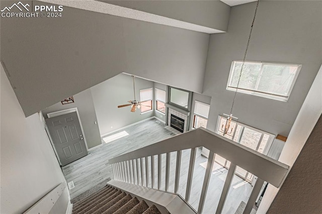 stairway with plenty of natural light, a high ceiling, ceiling fan, and hardwood / wood-style flooring