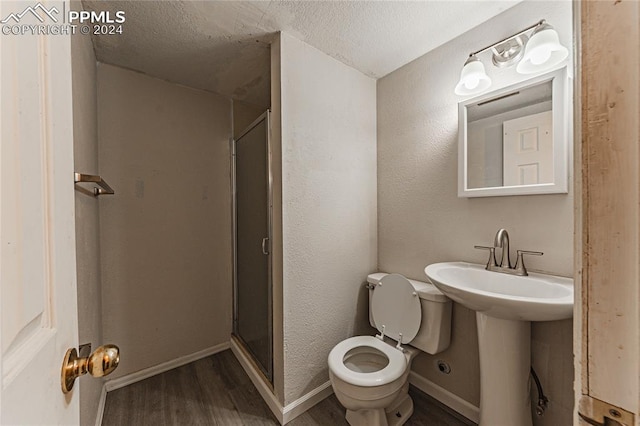 bathroom with walk in shower, a textured ceiling, wood-type flooring, and toilet