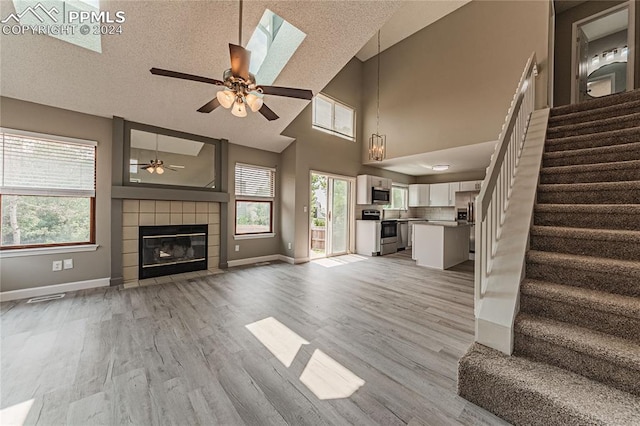 unfurnished living room with a fireplace, a textured ceiling, ceiling fan, and light hardwood / wood-style floors