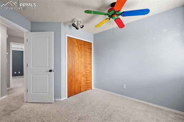 unfurnished bedroom with ceiling fan, light colored carpet, a textured ceiling, and a closet