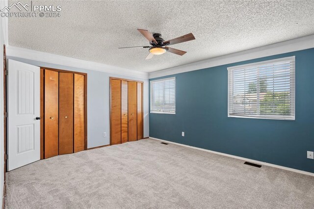 carpeted spare room with ceiling fan and a textured ceiling