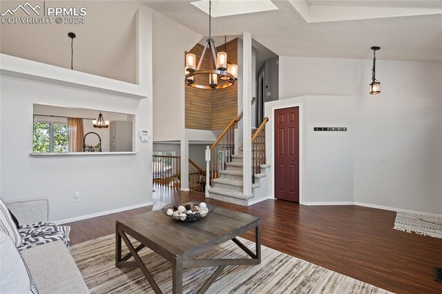 unfurnished living room with a notable chandelier, high vaulted ceiling, a textured ceiling, and dark hardwood / wood-style flooring