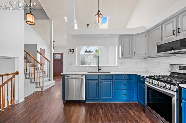 kitchen with stainless steel appliances, dark wood-type flooring, blue cabinetry, and decorative light fixtures