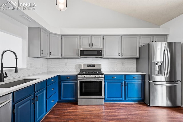 kitchen with appliances with stainless steel finishes, vaulted ceiling, sink, and dark hardwood / wood-style flooring