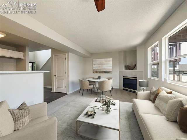 living room featuring a tiled fireplace and a textured ceiling