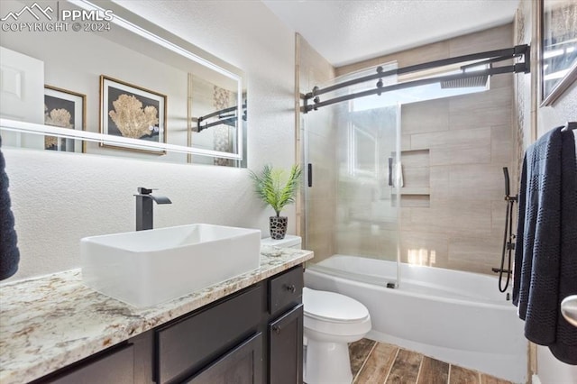 7848 Chasewood Loop, Colorado Springs, CO 80908 - bathroom with bath / shower combo with glass door, a textured wall, plenty of natural light, toilet, and wood finished floors