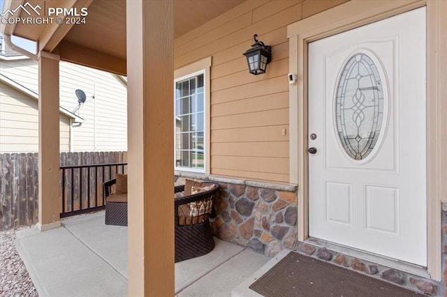 7848 Chasewood Loop, Colorado Springs, CO 80908 - doorway to property featuring fence, a porch, and stone siding
