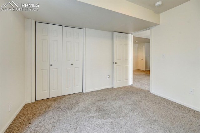 unfurnished bedroom with light carpet and a closet