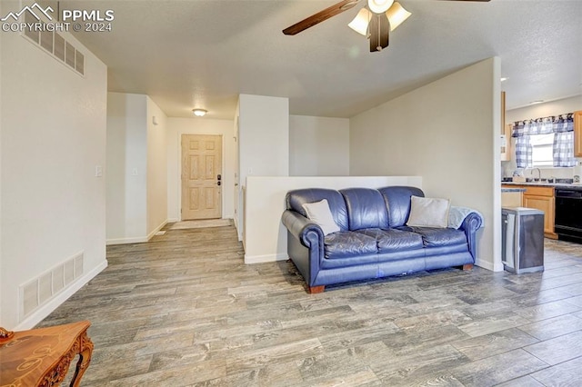 living room featuring ceiling fan, sink, and light hardwood / wood-style flooring