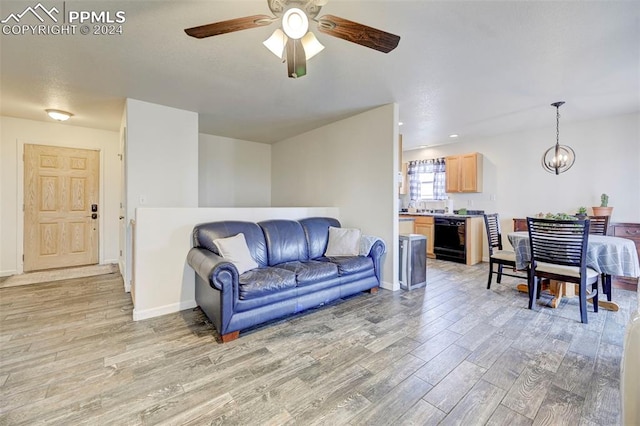 living room featuring ceiling fan with notable chandelier and light hardwood / wood-style floors