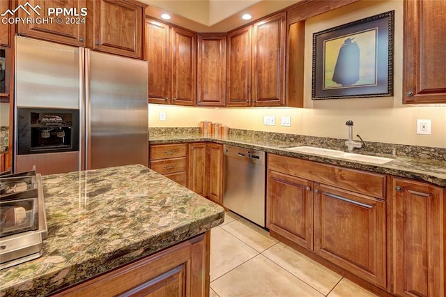 kitchen featuring sink, light tile patterned floors, stone countertops, and appliances with stainless steel finishes