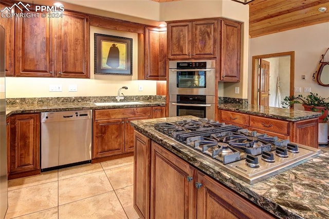 kitchen with sink, dark stone countertops, light tile patterned floors, wood ceiling, and stainless steel appliances