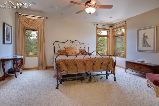 bedroom with multiple windows, ceiling fan, and light colored carpet