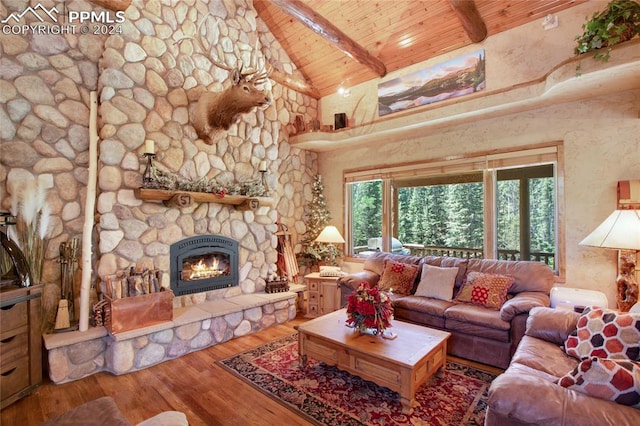 living room featuring hardwood / wood-style floors, a stone fireplace, beam ceiling, high vaulted ceiling, and wooden ceiling