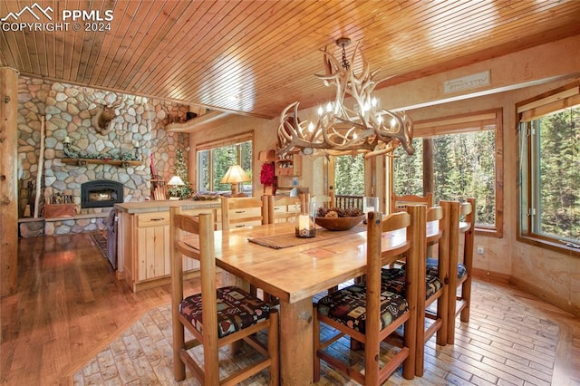 dining space featuring a fireplace, wooden ceiling, a chandelier, and hardwood / wood-style floors