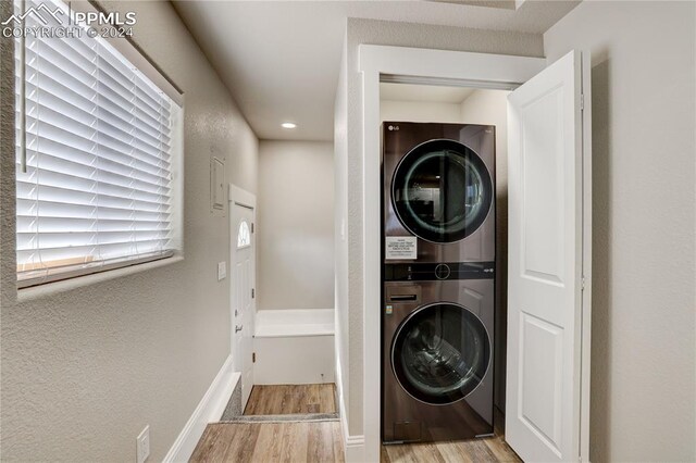 clothes washing area featuring stacked washer / drying machine and light hardwood / wood-style floors