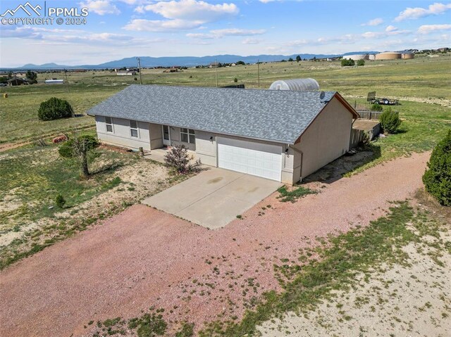 single story home with a garage, a mountain view, and a rural view