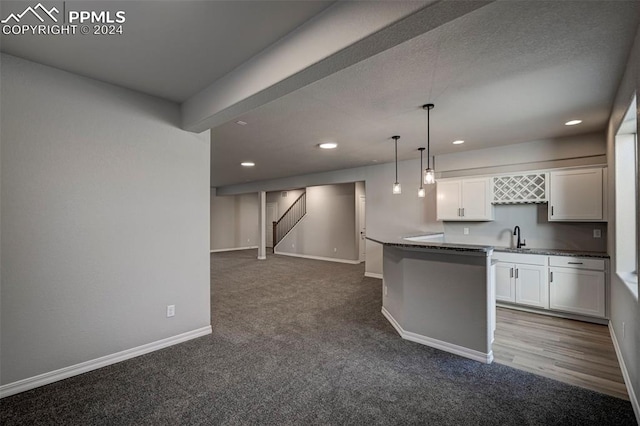 kitchen featuring decorative light fixtures, sink, white cabinets, carpet, and a center island