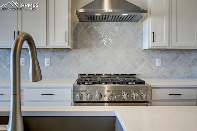 kitchen featuring white cabinets, stainless steel stove, wall chimney exhaust hood, and backsplash