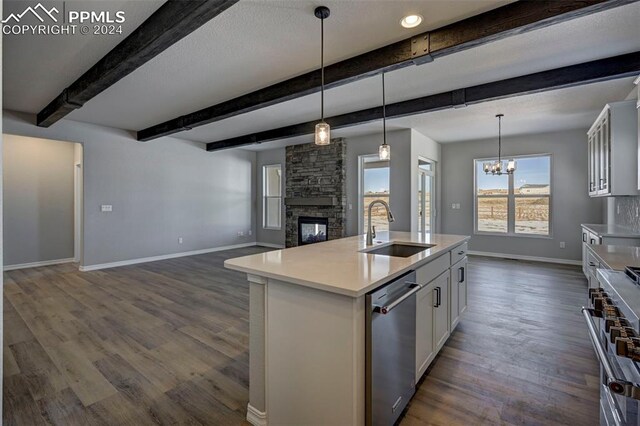 kitchen with white cabinetry, appliances with stainless steel finishes, sink, and a center island with sink