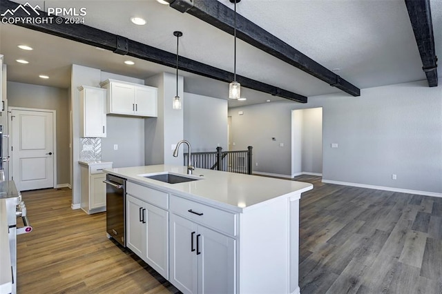 kitchen with decorative light fixtures, beamed ceiling, sink, white cabinets, and a kitchen island with sink