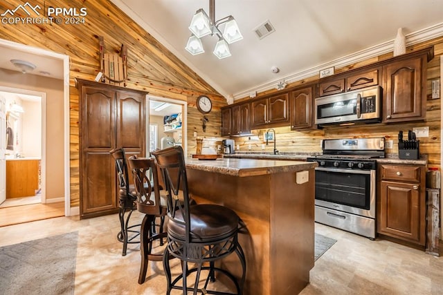 kitchen with a breakfast bar, a kitchen island, wooden walls, stainless steel appliances, and lofted ceiling