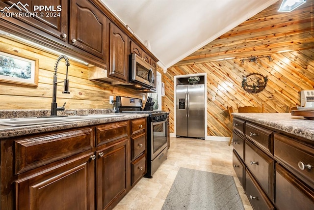 kitchen featuring wood walls, stainless steel appliances, sink, light tile patterned floors, and vaulted ceiling