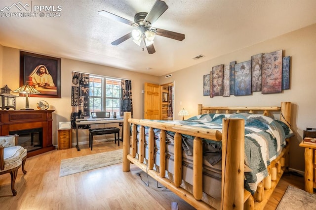 bedroom featuring light wood-type flooring, ceiling fan, and a textured ceiling