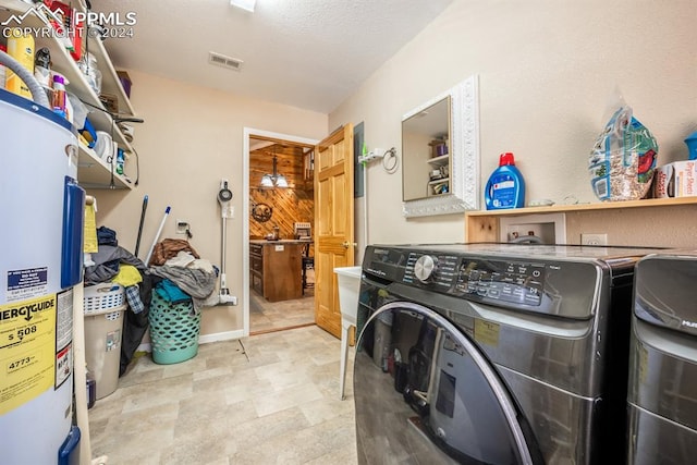 washroom featuring wood walls, water heater, light tile patterned floors, and washing machine and clothes dryer