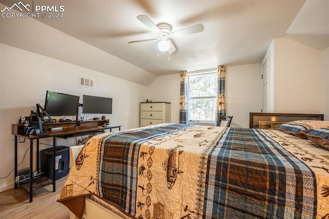 bedroom with ceiling fan, light wood-type flooring, a textured ceiling, and lofted ceiling