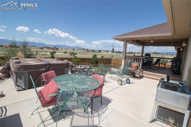 1933 Top Notch Trl, Penrose, CO 81240 - view of patio / terrace featuring a hot tub, fence, outdoor dining space, and a deck with mountain view