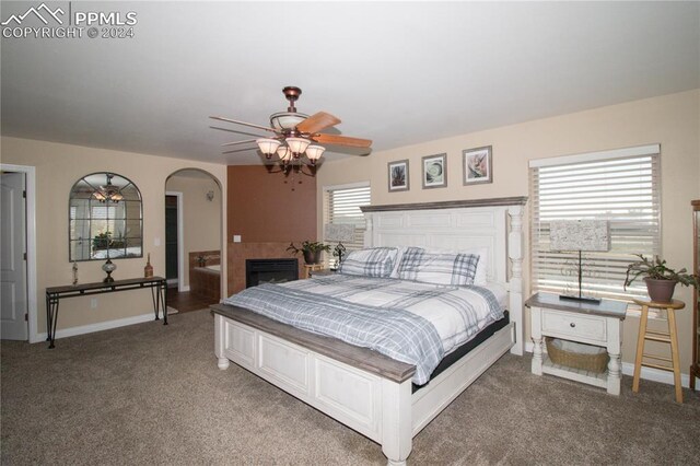 1933 Top Notch Trl, Penrose, CO 81240 - bedroom featuring a fireplace, light carpet, arched walkways, a ceiling fan, and baseboards
