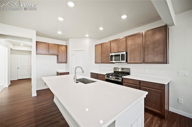 kitchen featuring recessed lighting, stainless steel appliances, dark wood-style flooring, a sink, and a center island with sink